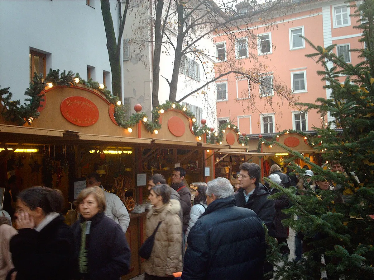 Illuminated Christmas market stalls in an Alpine square in Alto Adige — 1